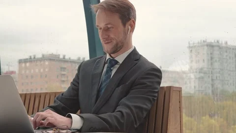 Businessman working using laptop, cowering area, city on background, rainy Stock Footage 196897206