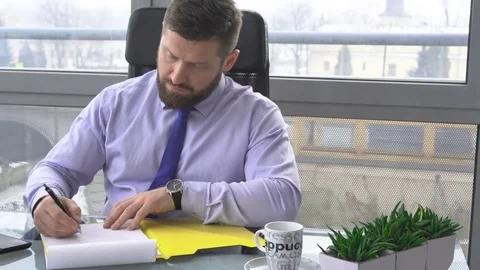 Businessman working writing with documents, in office, slider dolly forward shot Vídeos de archivo 73170500