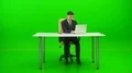 The businessman works at the desktop and phones on the green background 4k or 4k+ Resolution