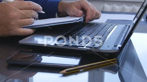 Businessman Write in Paper Documents Over the Laptop Keyboard Stock Photos