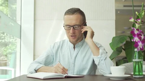 Businessman writing in daily planner while speaking on cellphone Stock Footage 79102281
