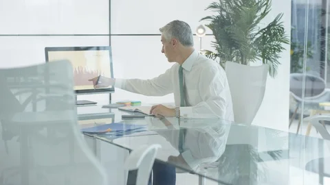 Businessman writing down notes while working on graph on computer Stock Footage 108073012