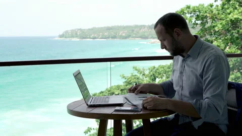 Businessman writing notes in documents on terrace, with sea view, 4K Stock Footage 102385969