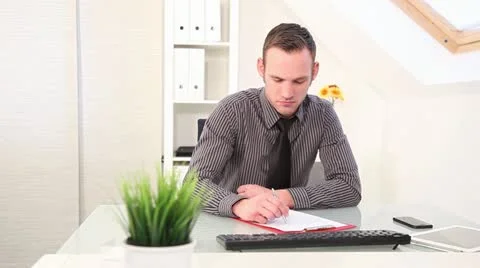Businessman writing notes at his desk Stock Footage 22001675