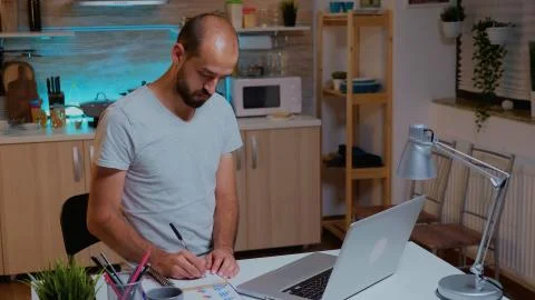 Businessman writing notes on notebook while working late Stock Photos