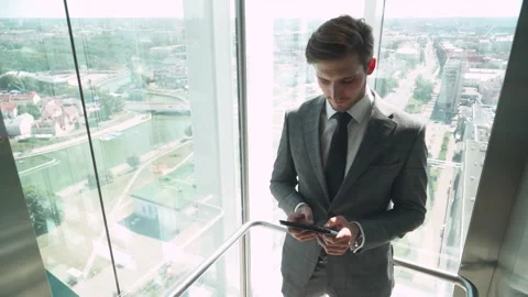 Businessman, young top manager goes to the top in the elevator and uses a screen Stock Footage 137223553