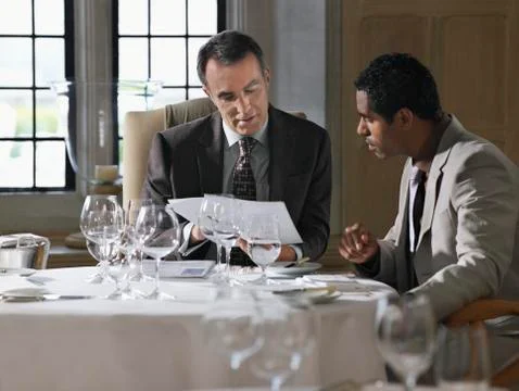 Businessmen Analyzing Documents At Restaurant Table Stock Photos