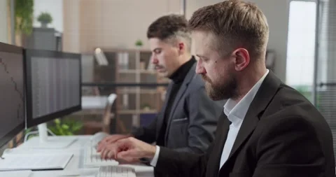 Businessmen analyzing reports at computers in office, finance teamwork analytics Stock Footage 331228726