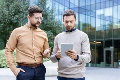 Businessmen discussing problem using tablet outdoors Foto stock