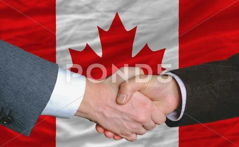 Businessmen handshake after good deal in front of canada flag Stock Photos