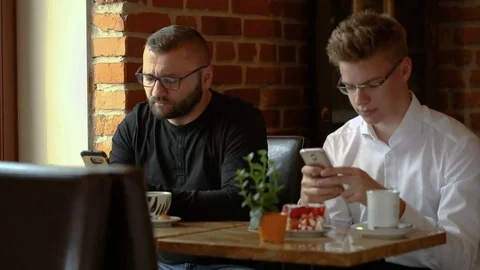 Businessmen sitting in the cafe and texting on smartphones Stock Footage 80425215