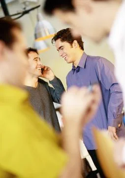 Businessmen standing, one using cell phone Stock Photos