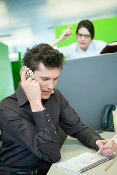 Businessmen talking on a mobile phone while his colleague looking angry Stock Photos