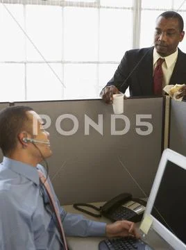 Businessmen talking over cubicle wall Stock Photos