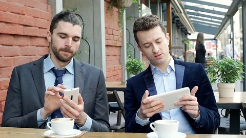 Businessmen using electronics and showing something to each other, steadycam sho Stock-Footage 74660144