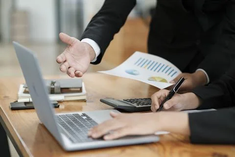 Businessmen working, discussing, analyzing using laptop and graphs. Stock Photos