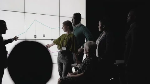 Businesspeople analyzing data on a digital wall in a dark office Stock Footage 138983617