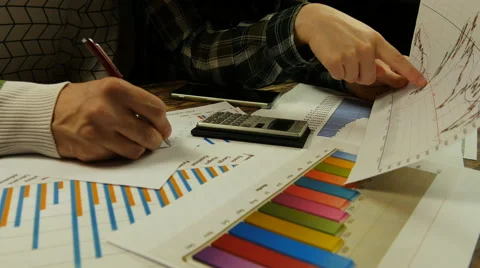 Businesspeople analyzing graphs, making calculations and taking notes Stock Footage 61790715