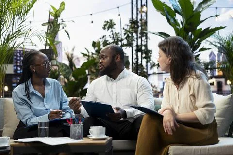 Businesspeople analyzing project documents, talking during networking event Stock Photos