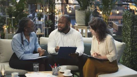 Businesspeople analyzing project documents, talking during networking event Stock Photos
