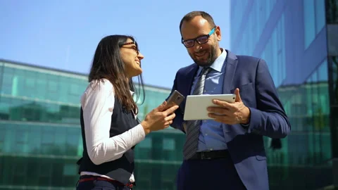 Businesspeople browsing internet on electronics and laughing, steadycam shot  Stock Footage 97133186