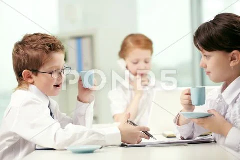 Businesspeople-like children drinking coffee and discussing documents in office Stock Photos
