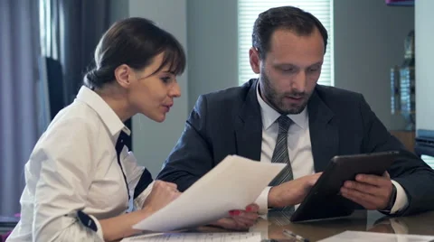 Businesspeople comparing data on tablet and documents by table in the office HD Stock Footage 57535870