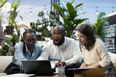 Businesspeople react with negative emotion to performance metrics on laptop Fotos Stock