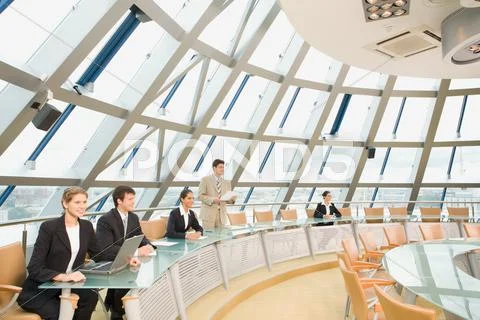 Businesspeople sitting at the round table listening to their colleagues speech Stock Photos