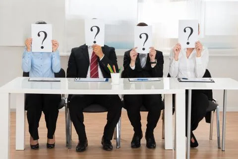Businesspeople Team Hiding Face With Question Mark Sign At Desk Stock Photos