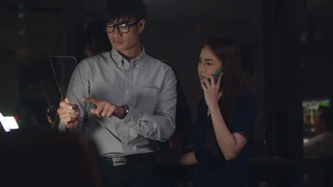 Businesspeople using phone while working together in creative night office. Stock Footage 126116434
