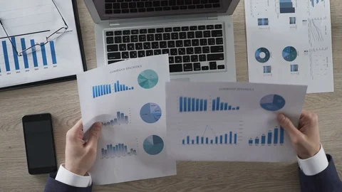 Businessperson comparing two graphs and entering data on laptop computer Stock Footage 74388404