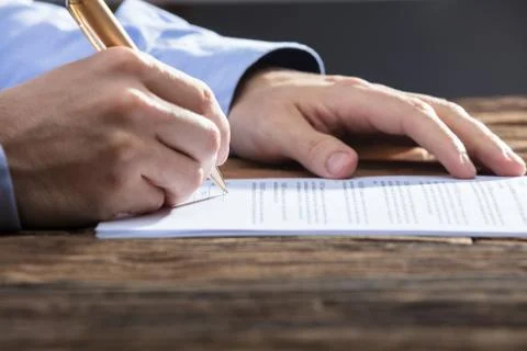 Businessperson's Hand Signing Document Stock Photos