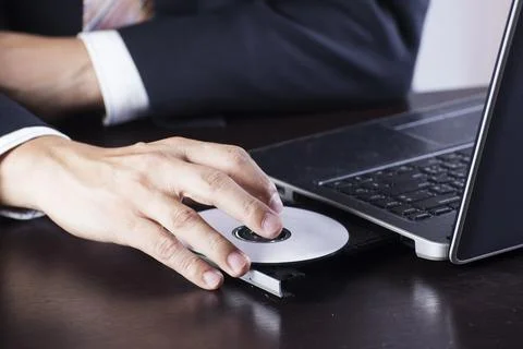 Business's hand holding Disk insert to laptop computer Foto stock
