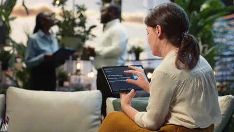 Businesswoman analyzes code using AI model on tablet in rooftop lounge Stock Footage 345165066