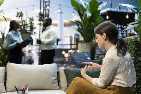 Businesswoman analyzes code using AI model on tablet in rooftop lounge Stock-Fotos
