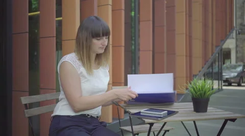 Businesswoman is browsing data in the folder, sitting on chair, outdoor. Steady. Stock Footage 65332307