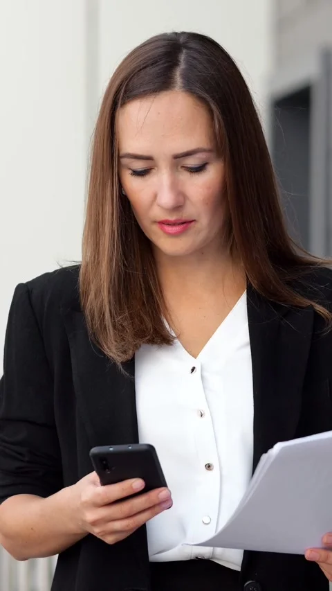 Businesswoman checking documents and using smartphone outdoors Stock Footage 341184198