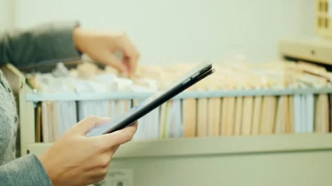 Businesswoman checking documents with tablet in office archive cabinet. Video stock 334560759