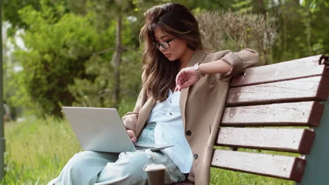 Businesswoman checking time while working on laptop in park Stock Footage 284759205