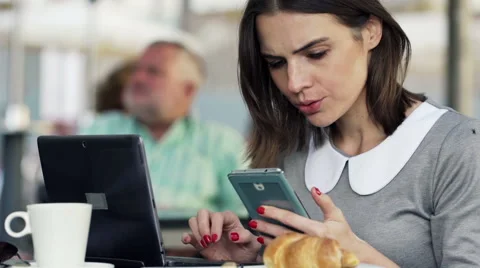 Businesswoman comparing data on smartphone and laptop in cafe city HD Stock Footage 47439341