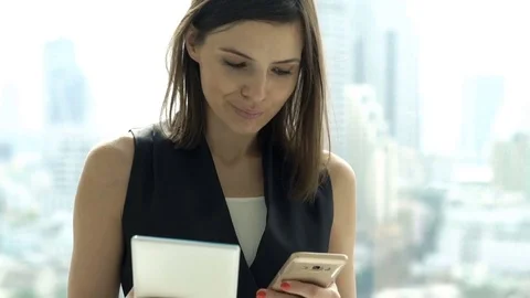 Businesswoman comparing data on tablet computer and smartphone in office Stock Footage 78089540