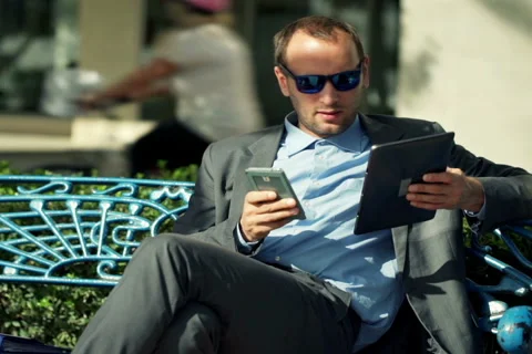 Businesswoman comparing data on tablet, smartphone sitting on the bench NTSC Stock Footage 44245336