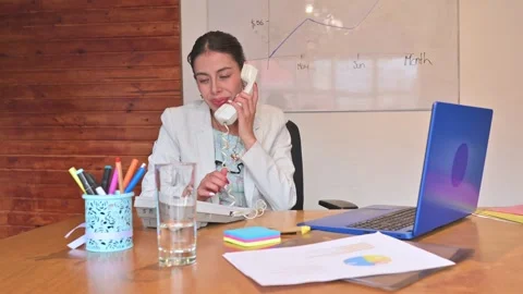 Businesswoman getting a call while working on a blue laptop. 動画素材 336286839
