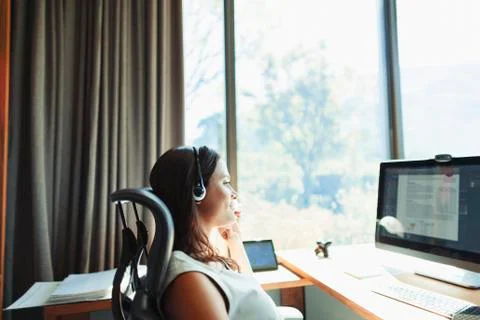 Businesswoman with headset working at computer in sunny home office Stock Photos