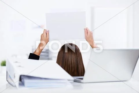 Businesswoman holding blank paper with binder and laptop on desk Stock Photos