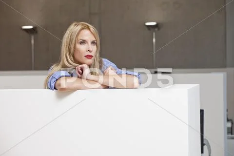 Businesswoman leaning on office cubicle and staring into distance Stock Photos