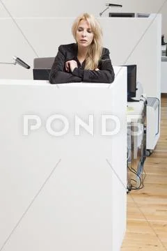 Businesswoman leaning on office cubicle looking down Stock Photos