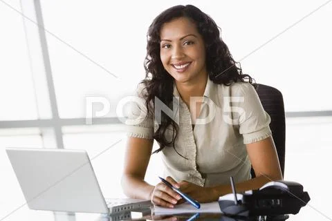 Businesswoman in office with laptop smiling (high key/selective focus) Stock-Fotos