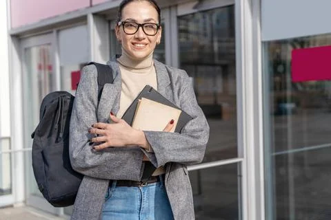 A businesswoman or student  in a jacket and jeans  holding books near unive.. Stock Photos